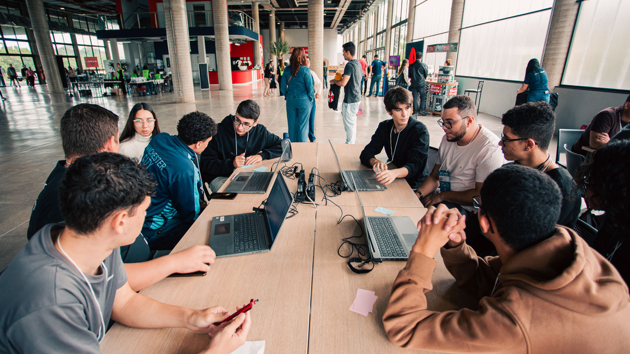 Jovens e orientadores trabalhando juntos no Hackathon Teckids 2024